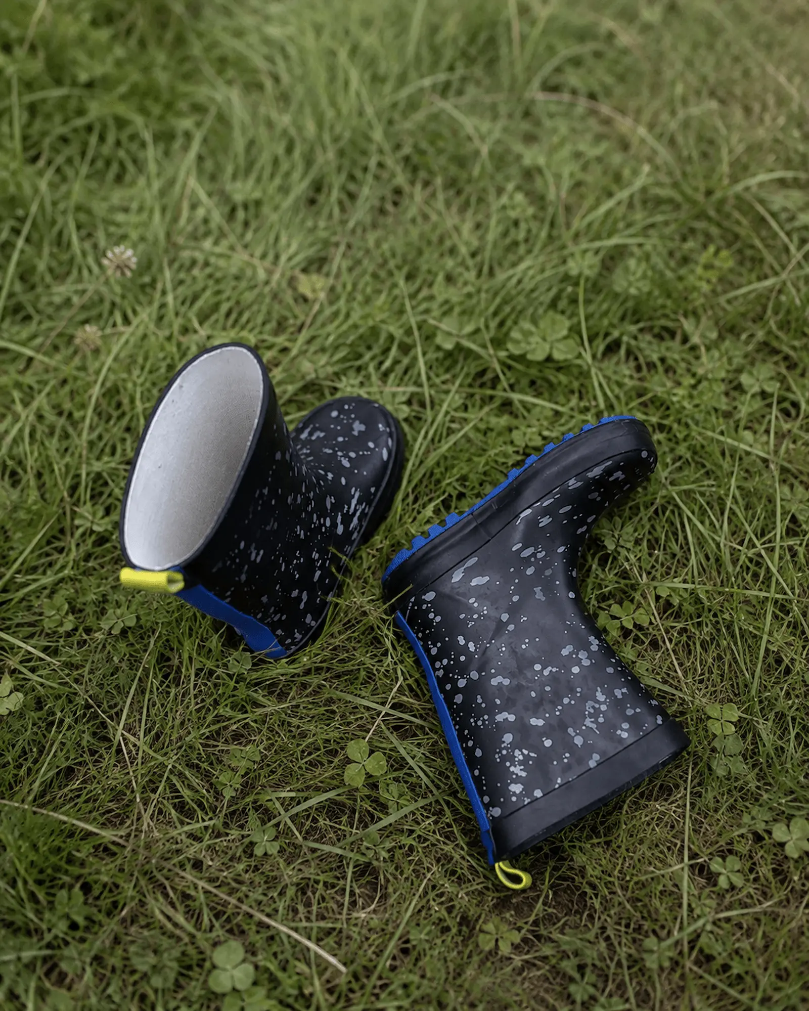 Kleine Gummistiefel liegen im Gras zwischen Kleeblättern – Zeit draußen an der frischen Luft tut der Haut bei Neurodermitis oft gut.